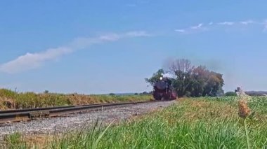 Ronks, Pennsylvania, June 2021 - Low Angle of a Steam Passenger Train With Smoke and Steam Passing on a Windy Summer Day