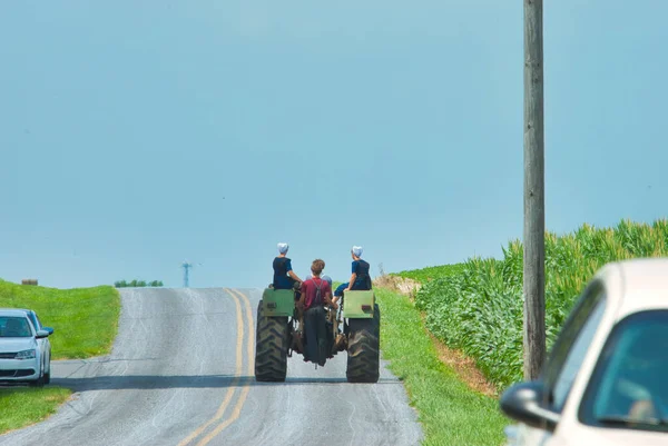 Amish Boy and Girl Teenagers Riding on a Old Tractor Thru Farmlands — Stockfoto