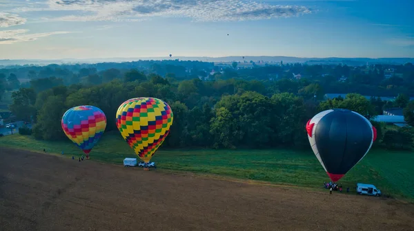 Multiple Hot Air Balloons Landing in Farmlands as Amish Look on — Zdjęcie stockowe