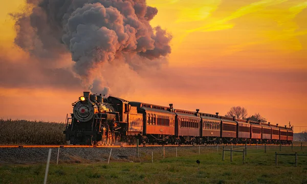 Vista de um antigo trem de passageiros a vapor Aproximando-se ao nascer do sol com uma cabeça cheia de vapor e fumaça — Fotografia de Stock