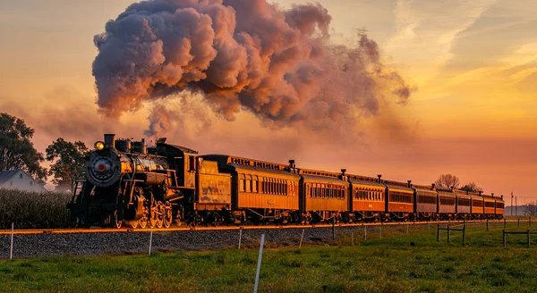 Veduta di un antico treno passeggeri a vapore che si avvicina all'alba con una testa piena di vapore e fumo — Foto Stock