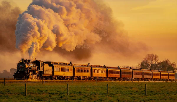 Вид на антикварный паровозный поезд, приближающийся к рассвету с полной головой пара и дыма — стоковое фото
