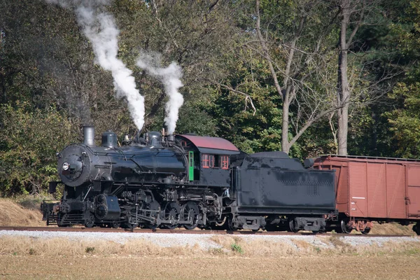 Antico treno merci a vapore che si avvicina su un singolo binario che soffia fumo — Foto Stock