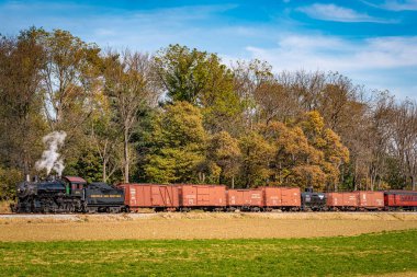 Ronks, Pennsylvania, November 8, 2021 - A View of a Steam Freight Train on a Single Track Going Thru Rural Countryside on a Sunny Day