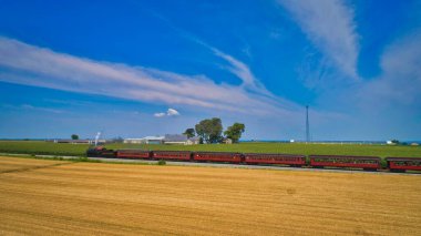 Ronks, Pennsylvania, July 24, 2021 - Aerial View of a Steam Passenger Train Approaching, Traveling Through Farmlands, With Corn and Wheat Fields, on a Beautiful Sunny Day.