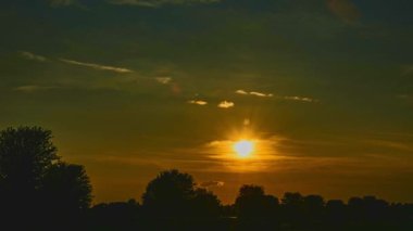 Timelapse of an Orange Sunset With Many Low Clouds Hiding and Peeking the Sun on a Summer Day