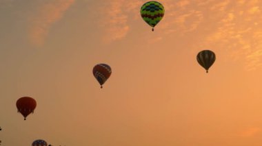 Multiple Hot Air Balloons Floating By at Different Highs on a Golden Early Morning Launch of Many Balloons