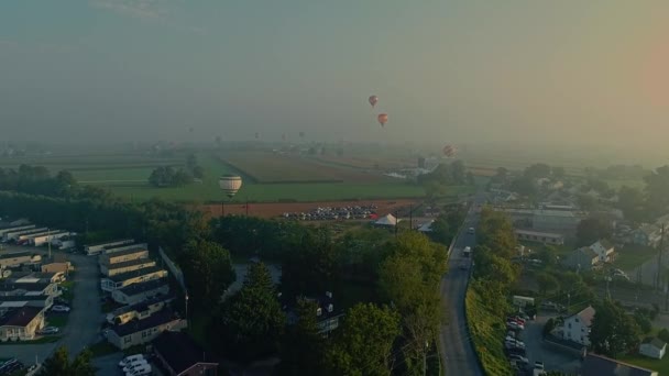 バルーンフェスティバル中の霧の朝に着陸場所を探している複数の熱気球のドローンビュー — ストック動画