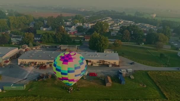 霧の中で農場やビジネスの近くに単一の熱気球着陸のドローン旋回ビュー朝 — ストック動画