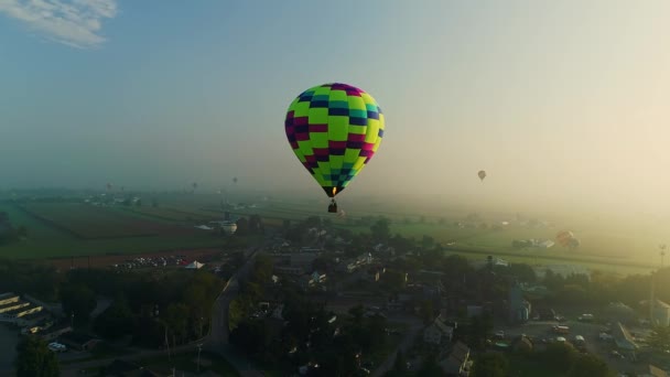 バルーンフェスティバル中の霧の朝に着陸場所を探している複数の熱気球のドローンビュー — ストック動画