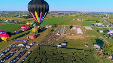 Drone Close Up View of Hot Air Balloons Passing By Over Farmlands and Businesses on a Sunny Day