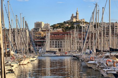 Yatlar, yelkenliler ve Fransa 'nın Marsilya limanındaki Notre-Dame de la Garde Kilisesi.
