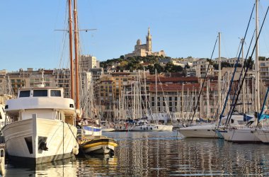 Yatlar, yelkenliler ve Fransa 'nın Marsilya limanındaki Notre-Dame de la Garde Kilisesi.