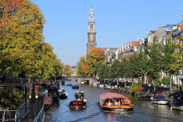 アムステルダム オランダ 2016年10月16日 人々は2016年10月16日にオランダのアムステルダムで秋の木とヴェスターケルク教会の塔の近くの運河を船で航海します — ストック写真