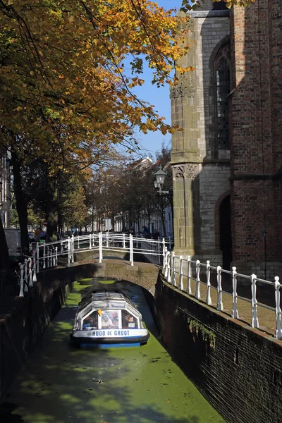 荷兰德尔夫特 2016年10月21日 2016年10月21日在荷兰德尔夫特的一条运河中 一艘船在一座桥下航行 一棵树上长着秋天的树叶 — 图库照片