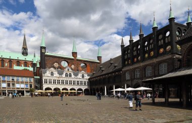 Lubeck, Almanya - 3 Temmuz 2019: Belediye binası ve diğer tarihi binalar ve 3 Temmuz 2019 'da Almanya' nın Lubeck kentindeki pazar yerinde yürüyen insanlar