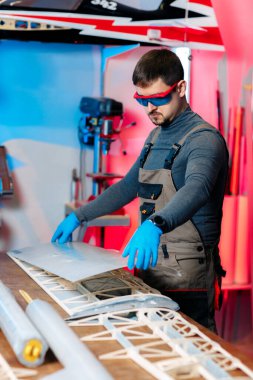 Erkek mühendis ya da teknisyen laboratuvarda İHA detayları üzerinde çalışıyor. GPS takibi yapabilen bir uçak. Karbon kanat.