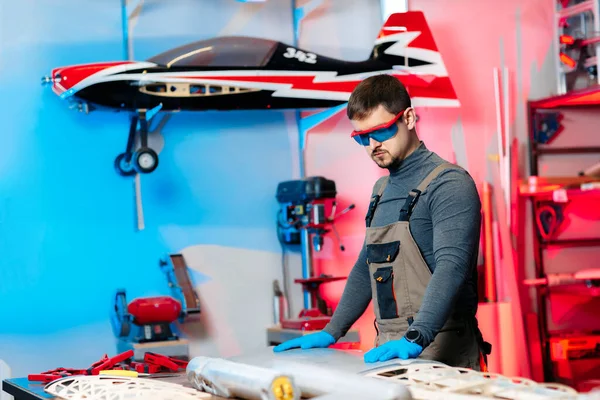 Junge männliche Ingenieure oder Techniker, die im Labor an Details der Drohne arbeiten. Flugzeuge, die GPS-fähig sind. Kohlenstoff. — Stockfoto