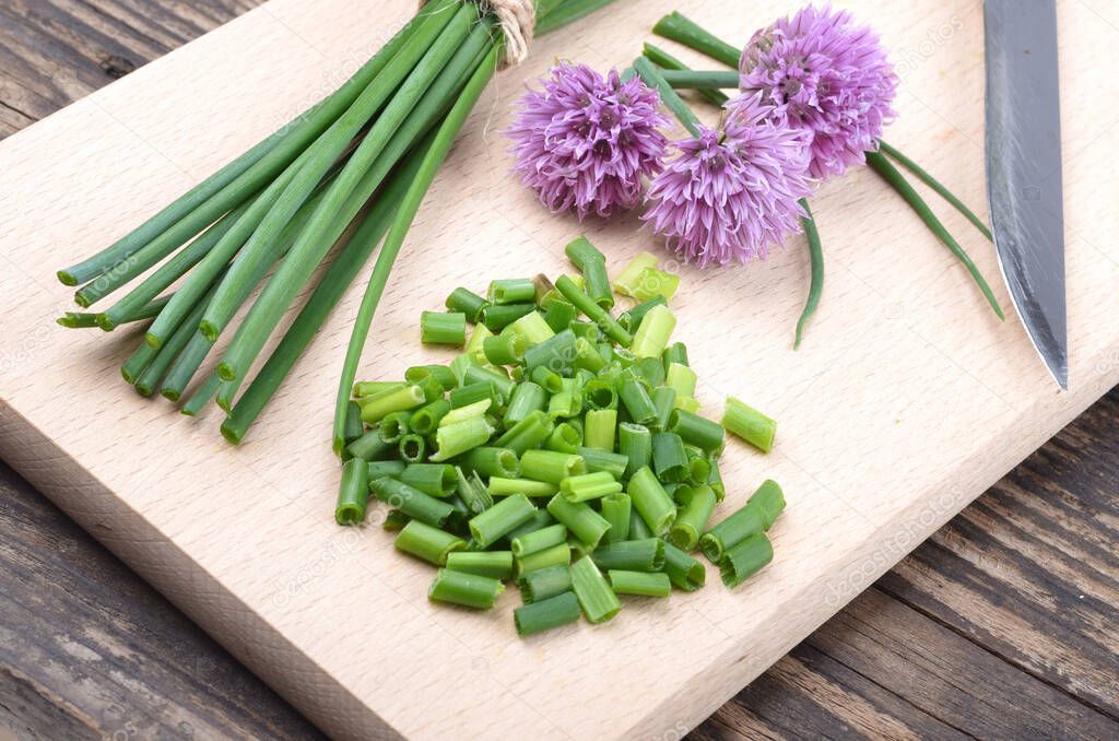 Siberian onion - Allium Schoenoprasum, cut on a plank. Vegetarian food and culinary use. Spices and fresh food.