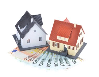 Miniature model of houses on stacked euro banknotes, on isolated white background. Real estate investment concept. Saving money for future retirement.