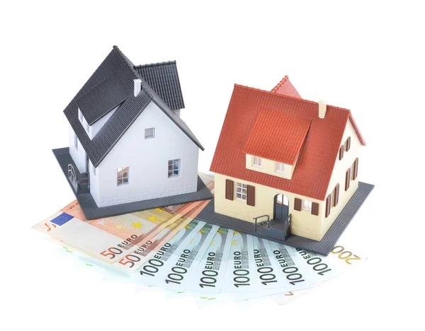 Miniature model of houses on stacked euro banknotes, on isolated white background. Real estate investment concept. Saving money for future retirement.