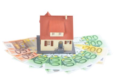 Miniature model of houses on stacked euro banknotes, on isolated white background. Real estate investment concept. Saving money for future retirement.