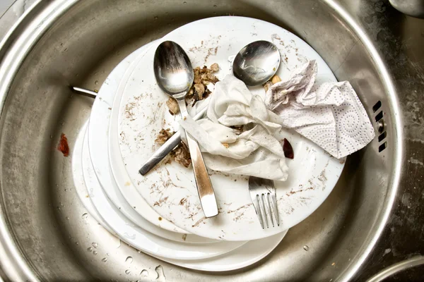 Colheres e garfo em pratos sujos na pia da cozinha Imagens Royalty-Free