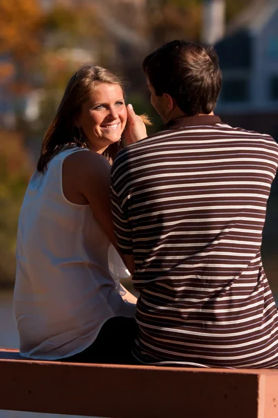 Man Caresses Sunlit Face Of Girlfriend Sitting On Bench — Stock Photo, Image