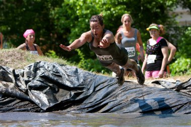 Woman Dives Into Mud Pit On Obstacle Course Run clipart
