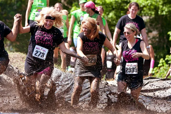 Vrouwen spetteren in modder put van hindernissenparcours uitvoeren — Stockfoto