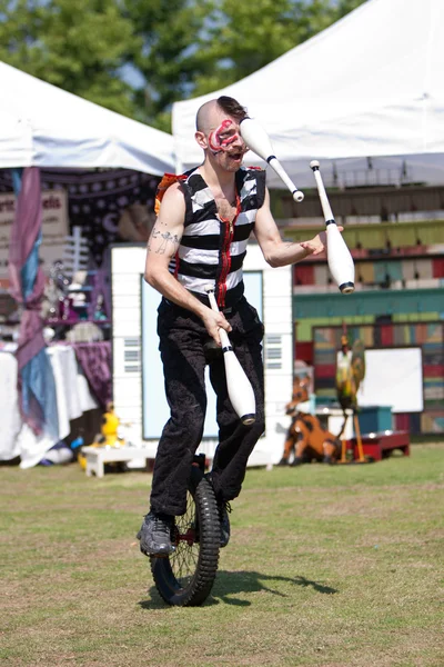 Цирковой артист жонглирует во время езды на велосипеде — стоковое фото