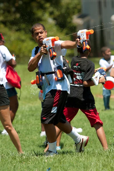 Man spuit in groep water gun automatische waterpistool strijd — Stockfoto