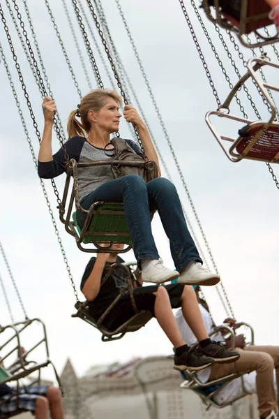 Volwassen vrouw rides schommels op county fair — Stockfoto