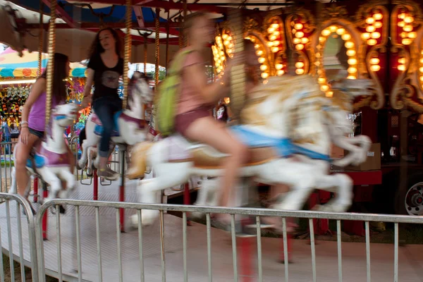 Bewegingsonscherpte van tieners rijden carrousel op beurs — Stockfoto