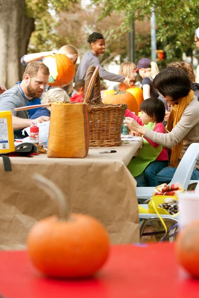 Eltern und Kinder schnitzen im öffentlichen Park Kürbisse — Stockfoto