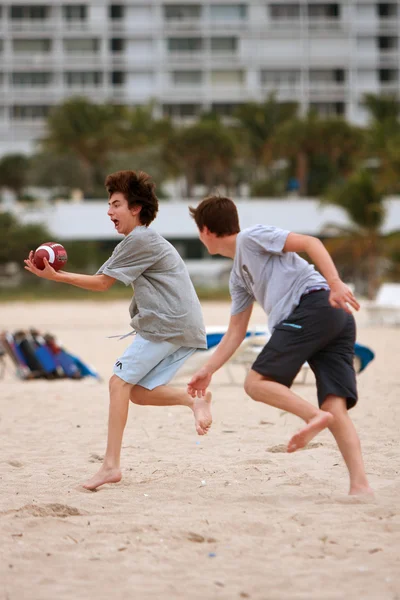 十几岁的男孩在沙滩足球游戏中捕获了球 — 图库照片