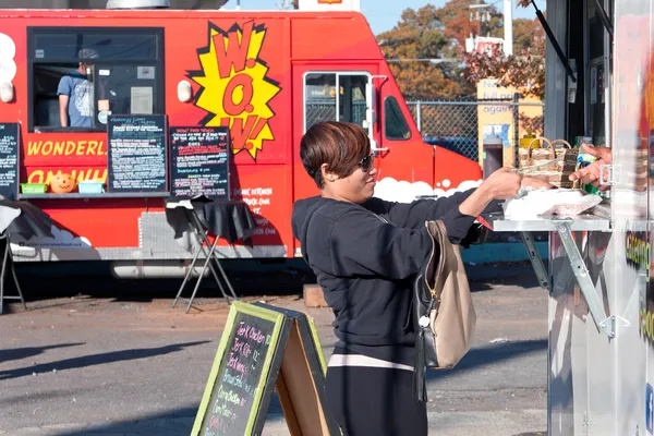 kadın doğrultusunda gıda kamyon satıcılar için bekler.