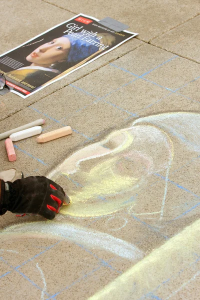 Художник мелом зарисовывает портрет на тротуаре — стоковое фото