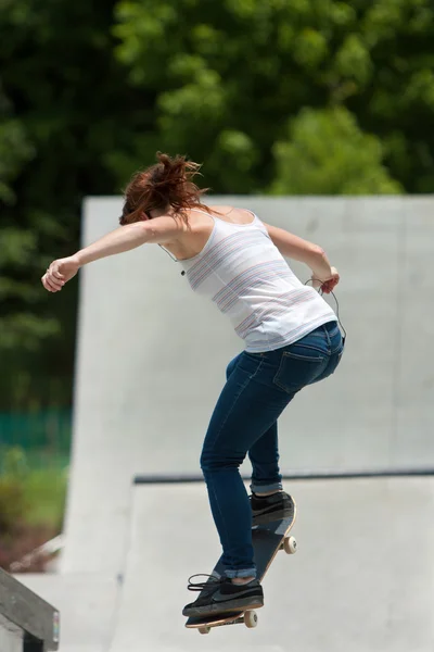 Adolescente chica realiza salto mientras practica skateboarding en parque —  Fotos de Stock