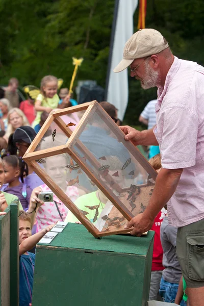 El hombre libera mariposas mientras los espectadores observan en el festival de verano —  Fotos de Stock