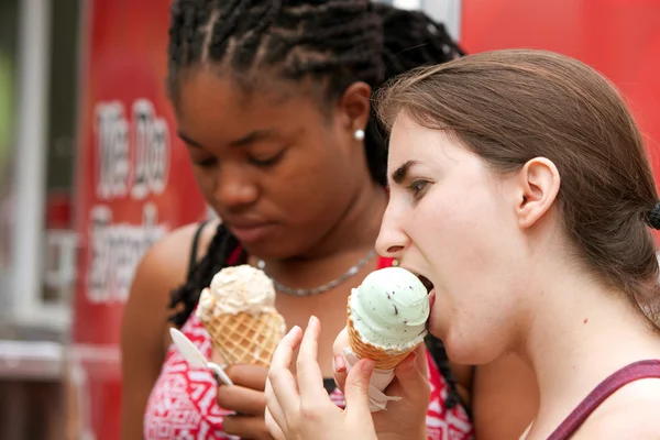 Unga kvinnor tycker om att äta glass strutar på sommarfestival — Stockfoto