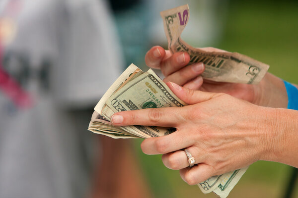 Руки торговца считают деньги, чтобы сделать изменения на фестивале
