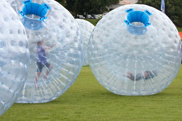 Gyerekek nyomja a nagy Zorbs körül füves területen nyári fesztiválon — Stock Fotó