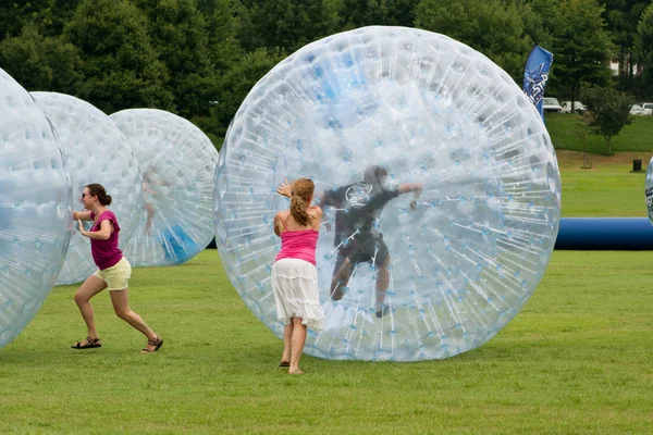 Nők nyomja a nagy Zorbs körül füves területen nyári fesztiválon — Stock Fotó