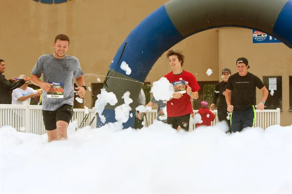 Male Runners Run Through Foam At Finish Line Of Race — Stock Photo, Image