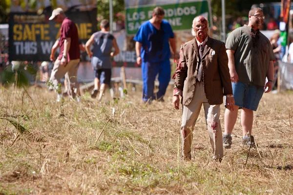 Älterer männlicher Zombie wartet darauf, Läufer im 5k-Rennen zu terrorisieren — Stockfoto