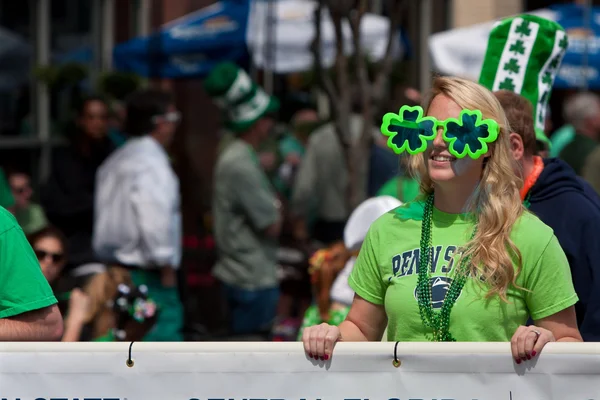 Mulher óculos de sol oversized shamrock carrega bandeira em desfile — Stockfoto