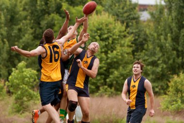Players Jump To Catch Ball In Australian Rules Football Game clipart