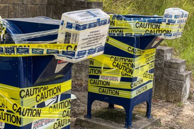 LAWRENCEVILLE, GA - JULY 8, 2022:  Outdoor mail drop boxes at a post office are taped shut with yellow caution tape and closed temporatily on July 8, 2022 in Lawrenceville, GA. clipart