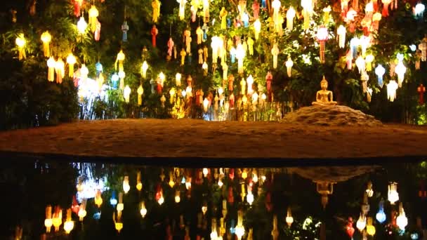 Guld buddha bild under vackra lantern träd och avspegling av damm — Stockvideo